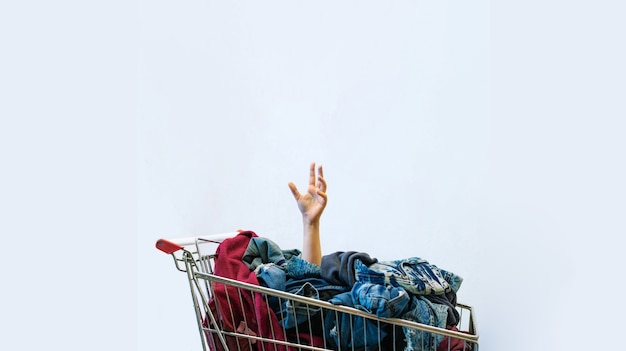 Female hand sticks out of shopping cart full of clothes