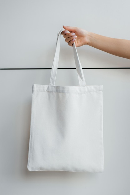 Photo female hand on the street holding white eco bag mock up