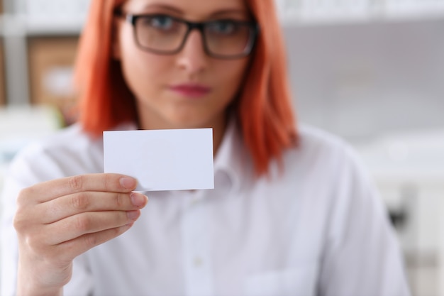 Foto la mano femminile in vestito dà il biglietto da visita in bianco