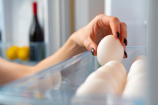 Female hand taking egg from a fridge