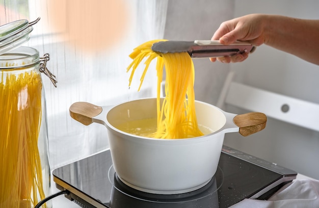 Female hand taking hot pasta out the pot