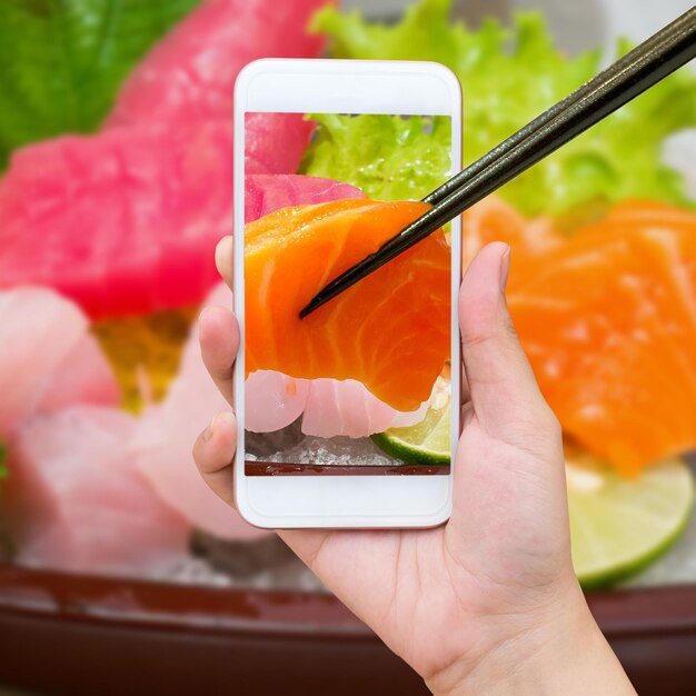 Foto mano femminile che cattura foto del set di sushi sashimi