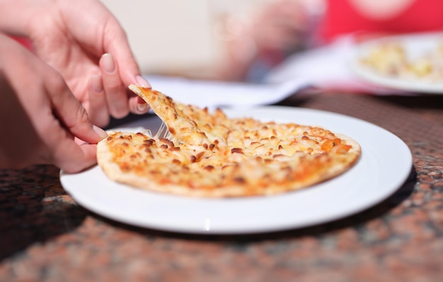 Female hand tearing off appetizing hot slice of pizza with cheese closeup