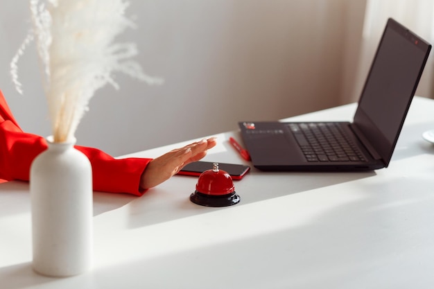 Female hand tends to press the red button on the table notepad and smartphone next to it