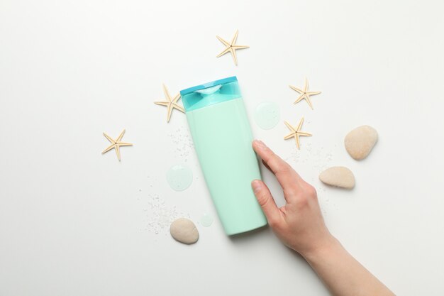 Female hand touches a bottle of shampoo on white background