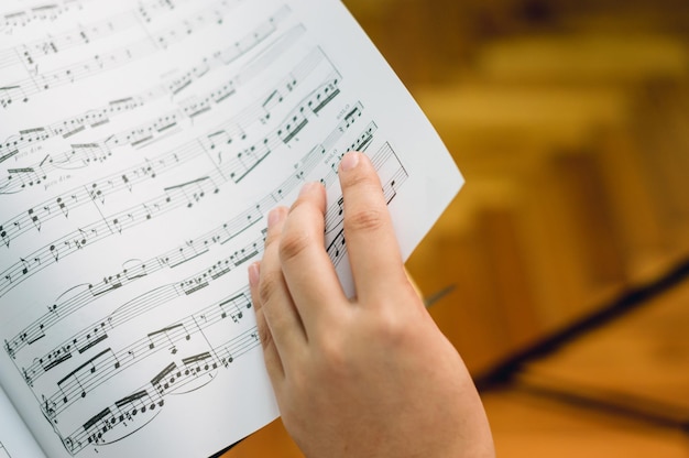 Photo female hand turning the page of sheet music first person perspective