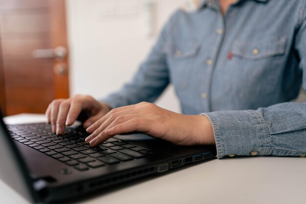 ラップトップのキーボードで入力する女性の手