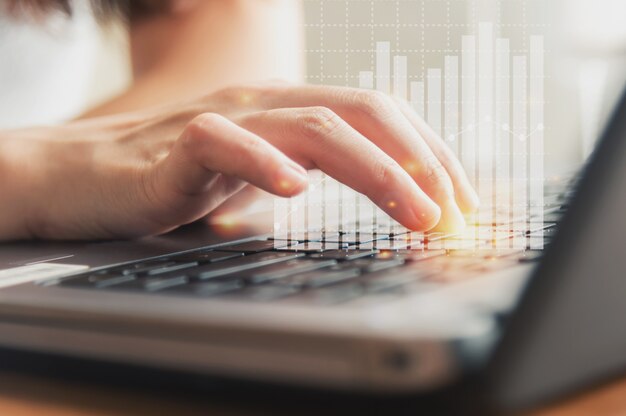 Female hand using keyboard with financial graph