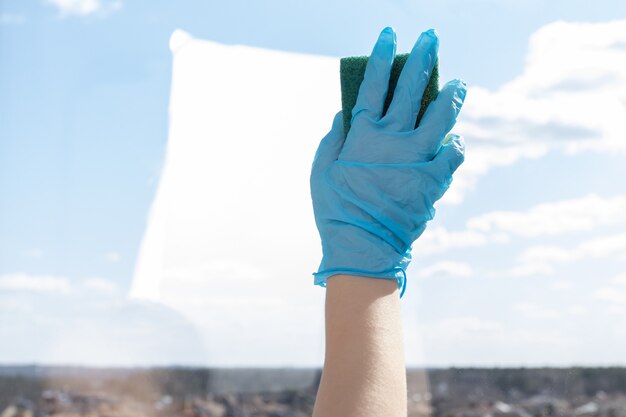 Female hand washes a window with a sponge