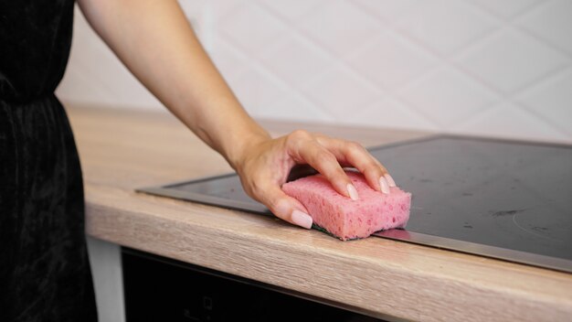 Female hand washing electric hob in the modern kitchen