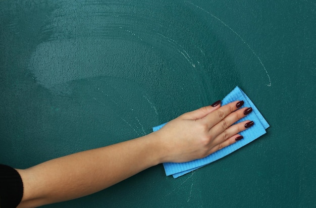 Photo female hand wiping blackboard closeup