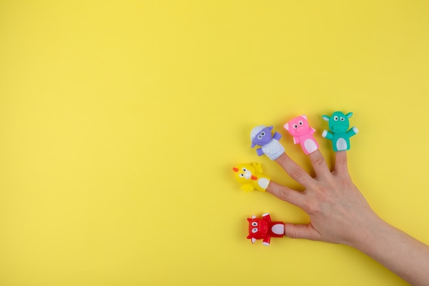 Foto mano femminile con bambole a 5 dita: mucca, pecora, pollo, maiale. il concetto di sviluppo del bambino. luogo da copiare. lay piatto.