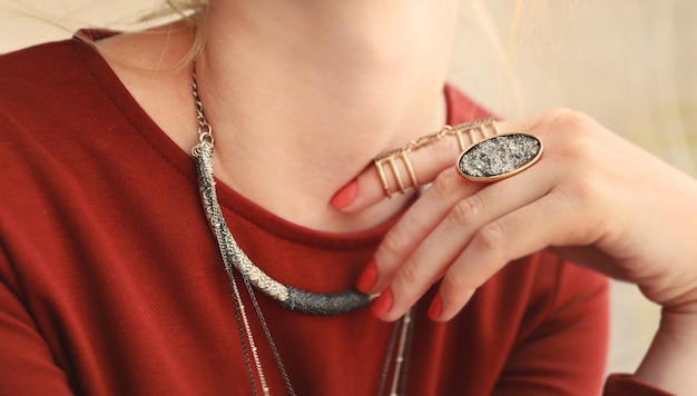 Female hand with beautiful accessories holding necklace close up