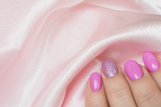 Female hand with a beautiful manicure holding satin fabric