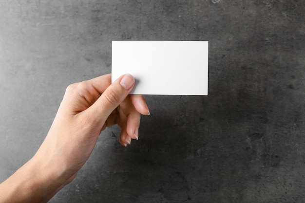 Female hand with blank business card on grey