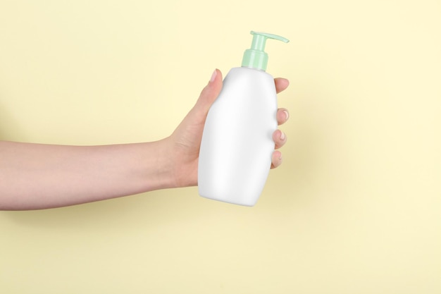 色の背景にシャワーのための化粧品のボトルと女性の手