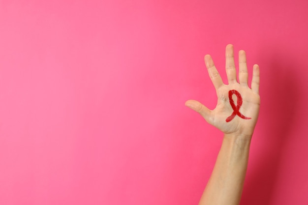 Female hand with breast cancer awareness sign on pink background