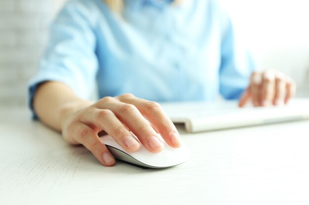 Female hand with computer mouse on table closeup