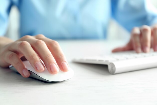 Female hand with computer mouse on table closeup