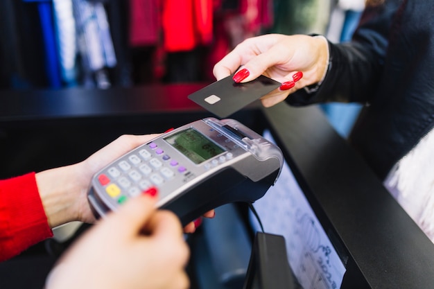 Foto mano femminile con la carta di credito che paga tramite il terminale per il pagamento nel negozio