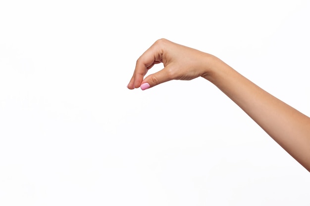 Female hand with a delicate pink manicure makes a gesture like holding something on white background