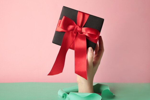 Female hand with gift box punching through the pink paper