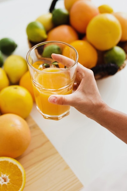 絞りたてのオレンジジュースのグラスと女性の手