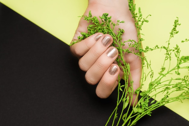 Фото Женская рука с золотым дизайном ногтей. золотая рука. женская рука на зеленой черной поверхности.