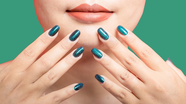 Female hand with green nail design on green background Woman manicure is art beautiful summer style Closeup of healthy young girl beauty fingers