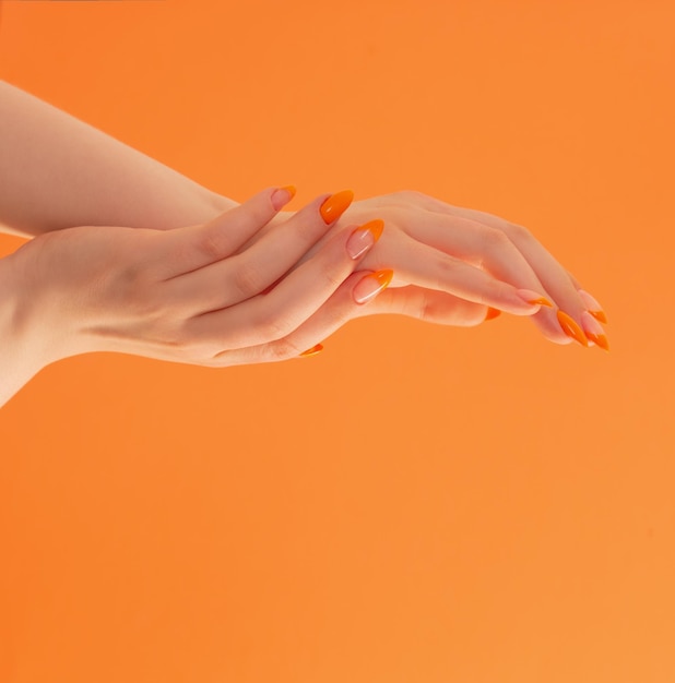 Foto mano femminile con manicure su sfondo arancione