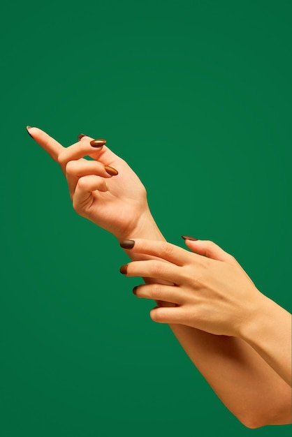 Female hand with manicure and soft healthy skin against green background taking care after hands