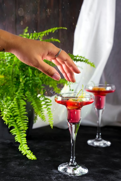 Female hand with margarita cocktail garnished with a macaroons and berries 