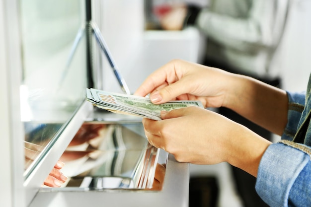 Женская рука с деньгами в окне кассы Концепция обмена валюты