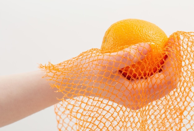 Female hand with orange and synthetic string bag