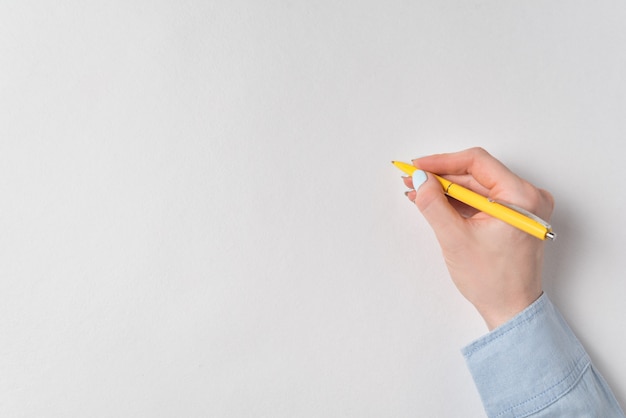 Foto mano femminile con la penna su fondo bianco. copia spazio