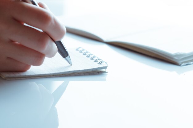 Female hand with pen writing in notebook