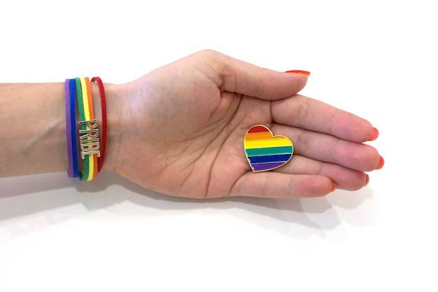 Female hand with a pride bracelet holds a rainbow heart LGBT concept Heart shaped rainbow icon