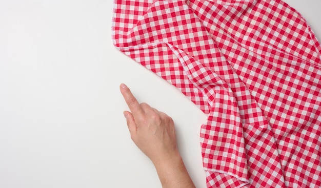 Female hand with raised forefinger and red kitchen napkin on white table, top view