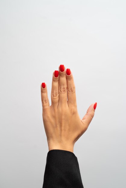 Foto la mano femminile con il manicure rosso mostra il gesto su fondo bianco