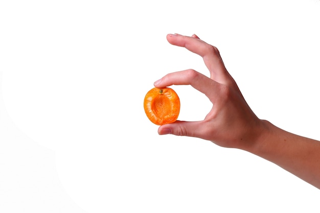 Женская рука с вкусным абрикосом на белом фоне. крем для рук и лечения или идея и концепция органической здоровой пищи