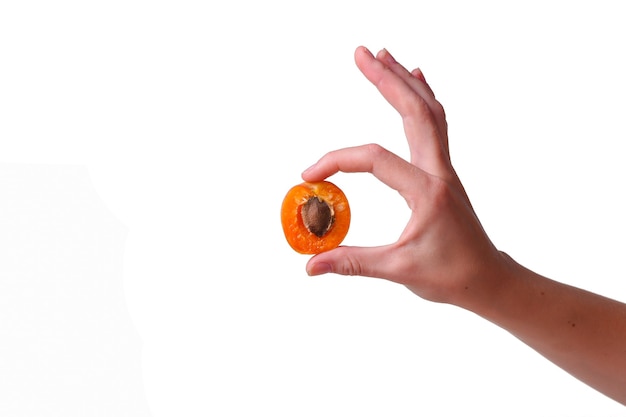 Photo female hand with tasty apricot on white background. cream for hands and treatment or organic healthy food idea and concept