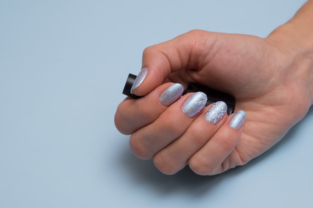 Female hand with winter manicure and a bottle of nail polish