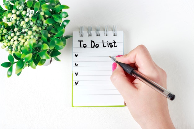 Female hand writes To Do List in notebook