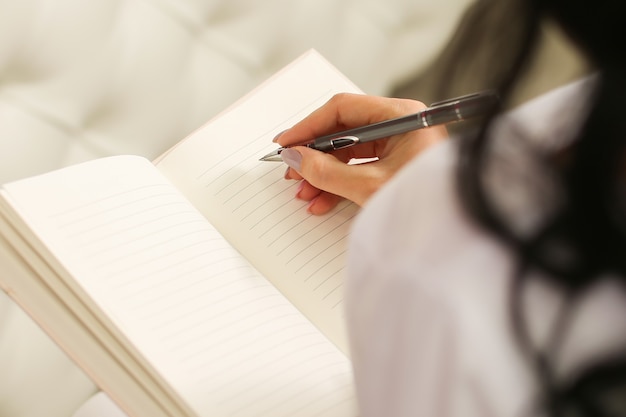 Female hand writes notes in a notebook.