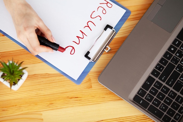 Photo female hand writes resume with lipstick on white sheet of paper