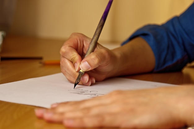 女性の手が縞模様の白い紙に真っ黒なペンで書き込みます。