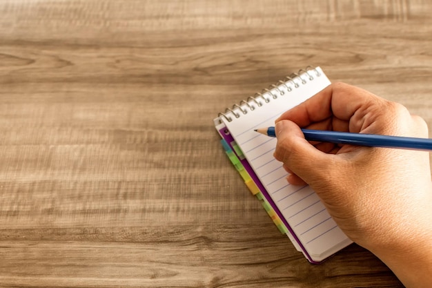 Female hand writing in a notebook on wooden table