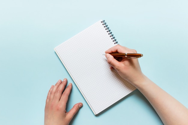 Scrittura femminile della mano con una penna su un taccuino