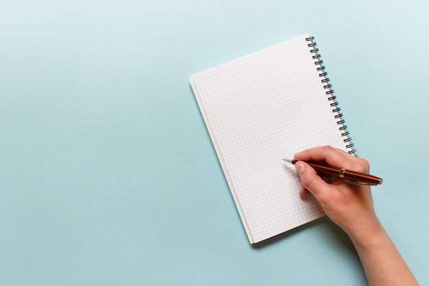 Female hand writing with a pen on a notebook