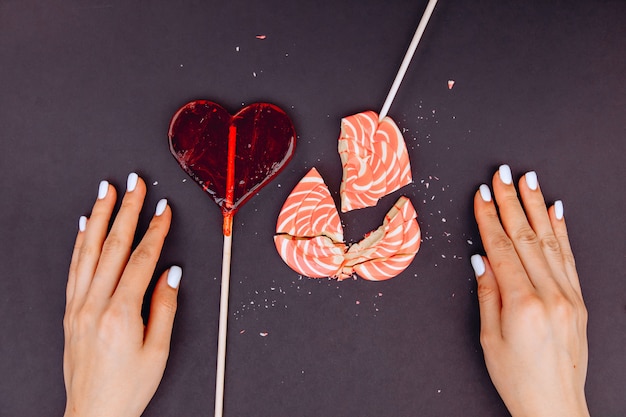 Female hands are trying to collect broken candy in the form of a heart